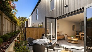 Una casa moderna con un patio, un'area salotto esterna e un'ampia vetrata scorrevole che conduce a un soggiorno interno.