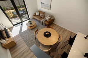 A modern living room with a sofa, coffee table, dining table, and chairs. - Prime Location with mountain views (Queenstown)