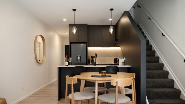 Una cucina moderna con zona pranzo, una scala e uno specchio a parete.