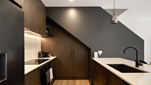 Una cucina moderna con mobili in legno scuro, un piano di lavoro bianco, un rubinetto nero e una lampada a sospensione.