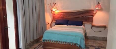 A bedroom with a checkered floor, a bed with a blue and white striped bedspread, a ceiling fan, and two wall-mounted lamps.