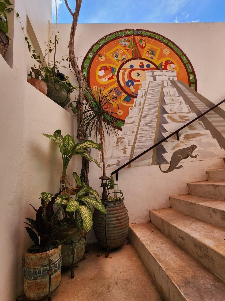 A staircase with a mural, potted plants, and a metal ladder.