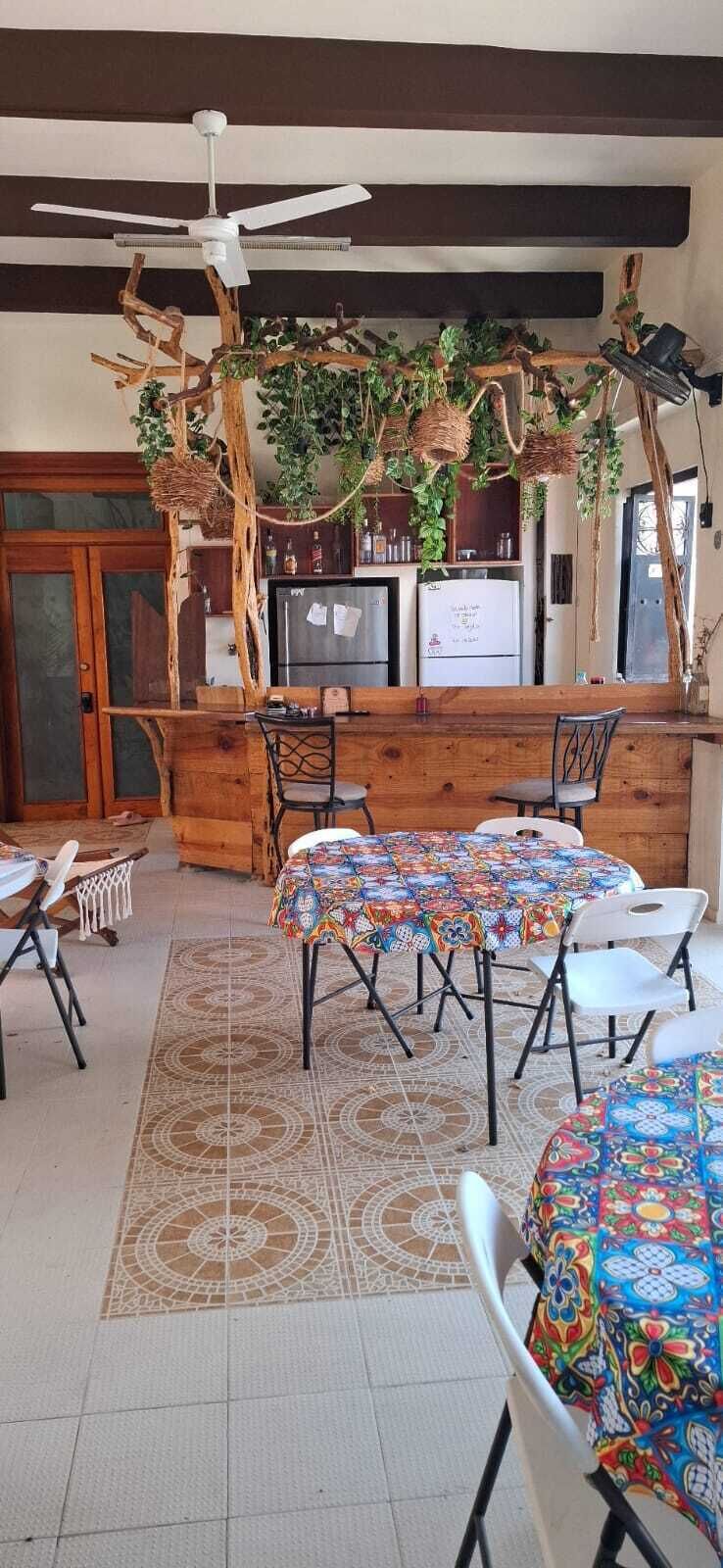 A rustic interior with a wooden bar, a ceiling fan, and a dining area with patterned floor tiles.