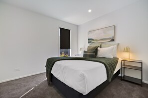 A bedroom with a bed, a nightstand, a painting, and a window with a view. - Prime Location with mountain views (Queenstown)