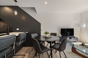 A modern living space with a dining area, a kitchen, and a seating area with a television. - Prime Location with mountain views (Queenstown)