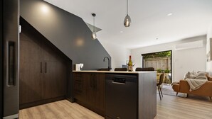A modern kitchen with dark cabinetry, a dishwasher, and pendant lighting. - Prime Location with mountain views (Queenstown)