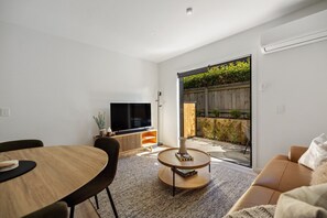 A modern living room with a TV, dining table, and sofa. - Prime Location with mountain views (Queenstown)