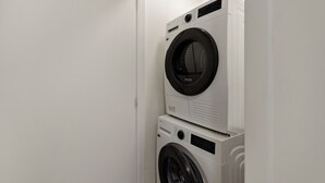 A compact, white laundry room with two stacked washing machines. - Prime Location with mountain views (Queenstown)
