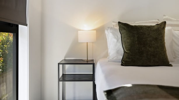 A hotel room with a bed, a nightstand with a lamp, and a window. - Prime Location with mountain views (Queenstown)