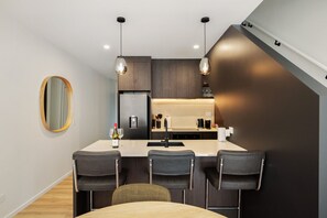 A modern kitchen with a central island, bar stools, pendant lighting, and a large mirror on the wall. - Prime Location with mountain views (Queenstown)