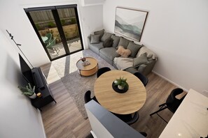 A modern living room with a sofa, a round wooden coffee table, and a dining area with chairs. - Prime Location with mountain views (Queenstown)