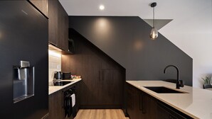 A modern kitchen with dark cabinetry, a wooden floor, a built-in oven, and a sink with a black faucet. - Prime Location with mountain views (Queenstown)