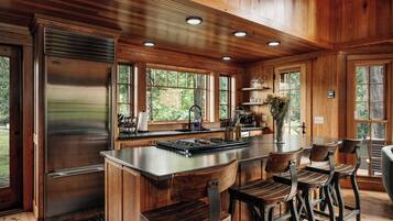 A wooden cabin interior with a kitchen island, bar seating, and a large refrigerator.