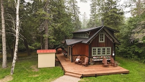 A cabin with a deck, surrounded by trees. - Magical Jordan River Oasis | Private Cabin & Deck (East Jordan)