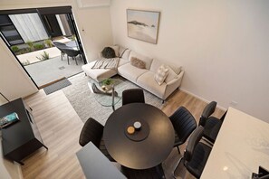 A modern living room with a sofa, a round table, and a dining area. - Prime Location with mountain views (Queenstown)
