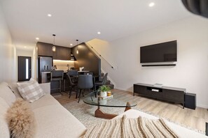 A modern living room with a sofa, a coffee table, and a TV mounted on the wall. - Prime Location with mountain views (Queenstown)