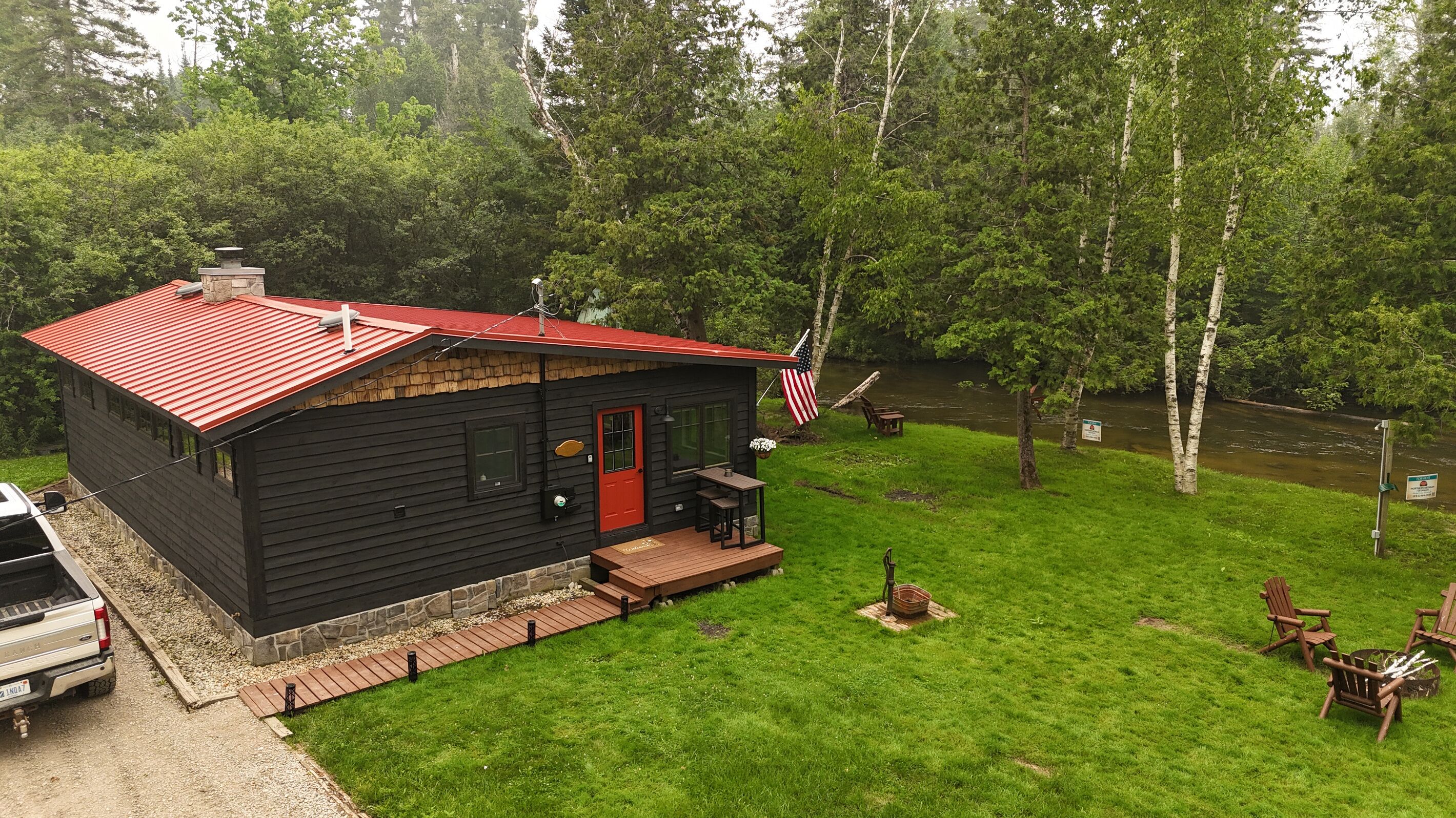 A cabin with a red roof, a front porch, and an American flag.