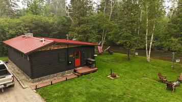 A cabin with a red roof, a front porch, and an American flag.