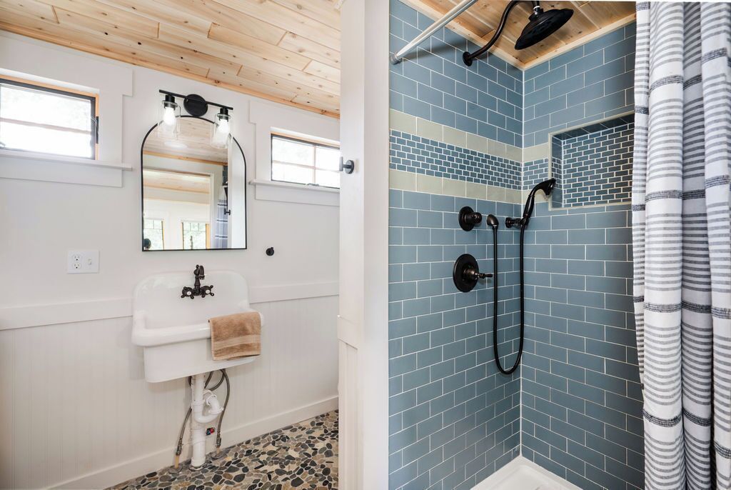 A bathroom with a white sink, mirror, and tiled shower area.