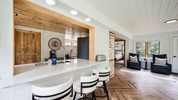 Une cuisine moderne avec un coin bar, des éléments décoratifs en bois et un motif de parquet en chevrons.