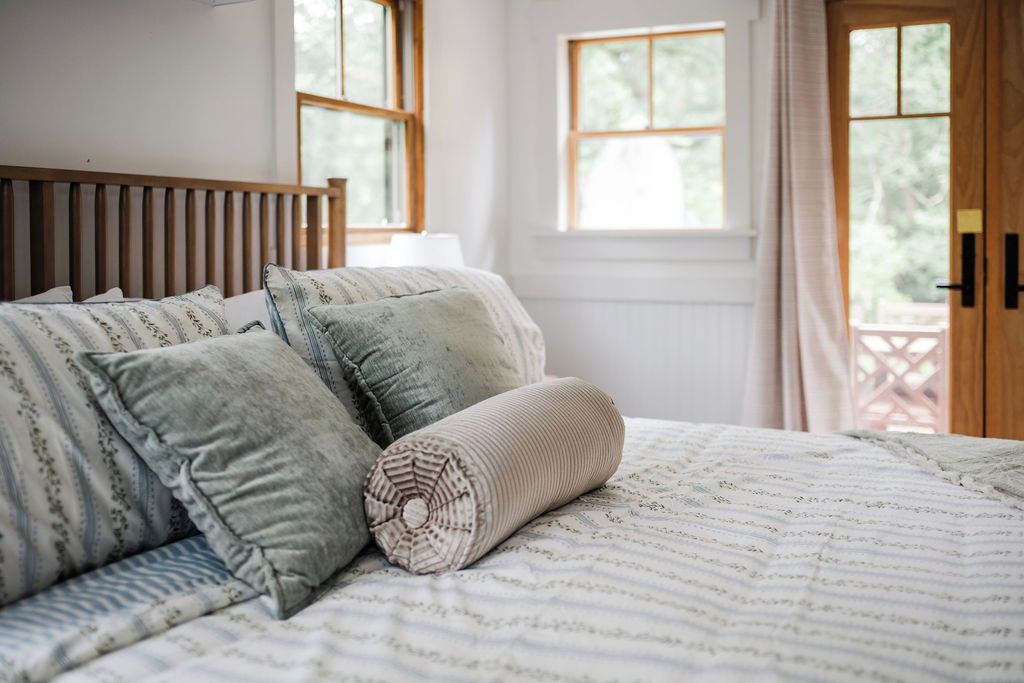 Una cama con colcha a rayas y almohadas, un cabecero de madera y vistas al exterior a través de una ventana.