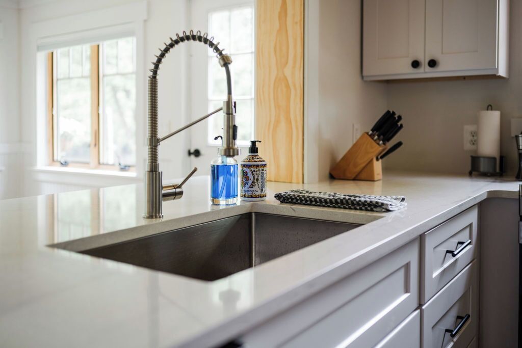 A kitchen with a modern faucet, a soap dispenser, and a knife block on the counter.