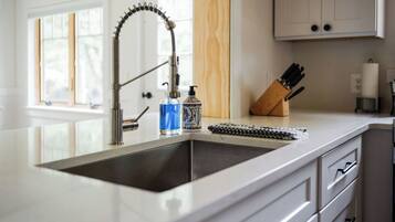 A kitchen with a modern faucet, a soap dispenser, and a knife block on the counter.