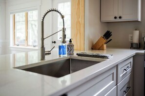 Une cuisine équipée d’un robinet moderne, d’un distributeur de savon et d’un bloc à couteaux posé sur le plan de travail.