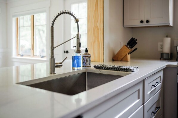 A kitchen with a modern faucet, a soap dispenser, and a knife block on the counter.