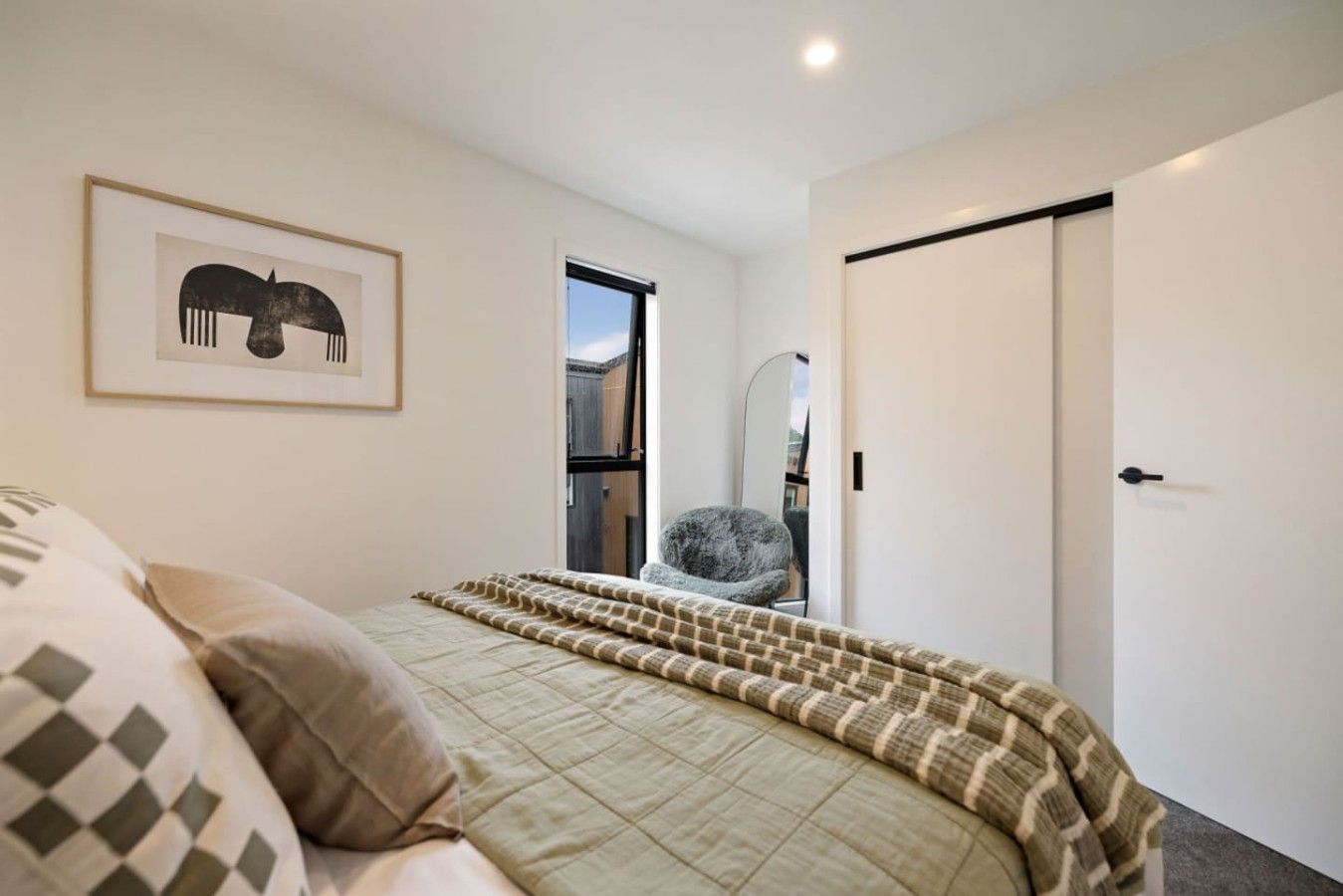 Une chambre à coucher avec un lit, une chaise, une porte et un tableau encadré au mur.
