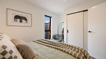 Une chambre à coucher avec un lit, une chaise, une porte et un tableau encadré au mur.