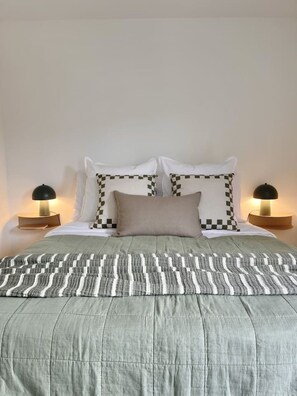 A bed with a patterned bedspread, two bedside lamps, and two pillows with a checkered design. - Kawarau Retreat, Queenstown (Queenstown)