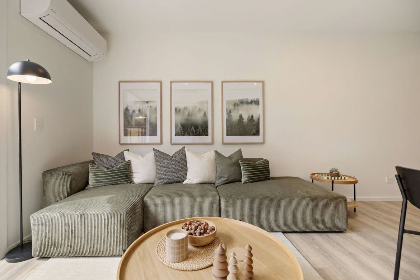 Un salon moderne avec un canapé d’angle, une table basse agrémentée d’objets décoratifs et des œuvres d’art encadrées accrochées au mur.