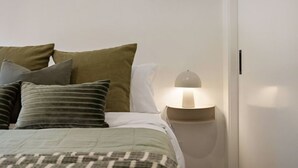 Ein Schlafzimmer mit einem Bett, Kissen, einer Nachttischlampe und einem Nachttisch.