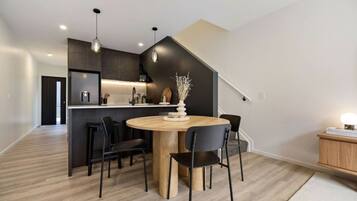 Une cuisine moderne avec des meubles de couleur sombre, un îlot central et des luminaires suspendus.