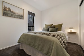 A bedroom with a bed, a window, a wall-mounted shelf, and a painting. - Prime Location with mountain views (Queenstown)