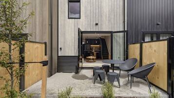 An outdoor seating area with a table and chairs, a wooden fence, and a small plant.