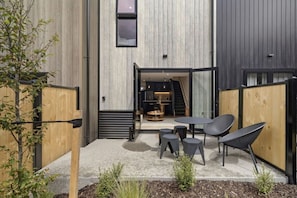 Een terras met een tafel en stoelen, een houten hekwerk en een plant.