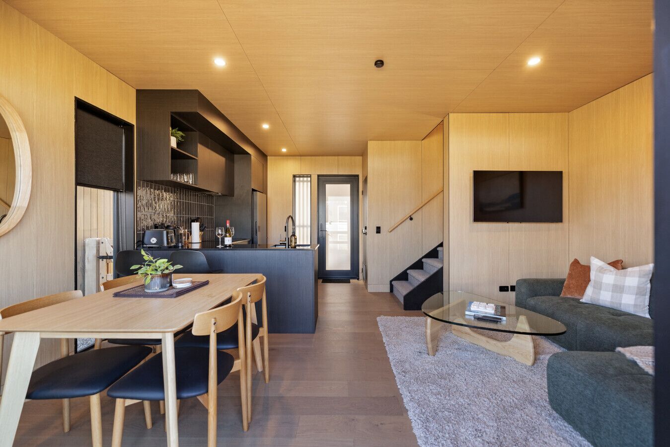 Un intérieur moderne comprenant un coin repas, une cuisine, un espace de vie et un escalier.