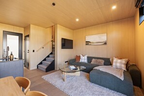 A modern living room with a sofa, a glass coffee table, and a staircase leading to another room. - Prime Location Luxury Villa (Queenstown)
