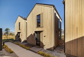 A modern wooden building with a central entrance, a side door, and a small window. - Prime Location Luxury Villa (Queenstown)