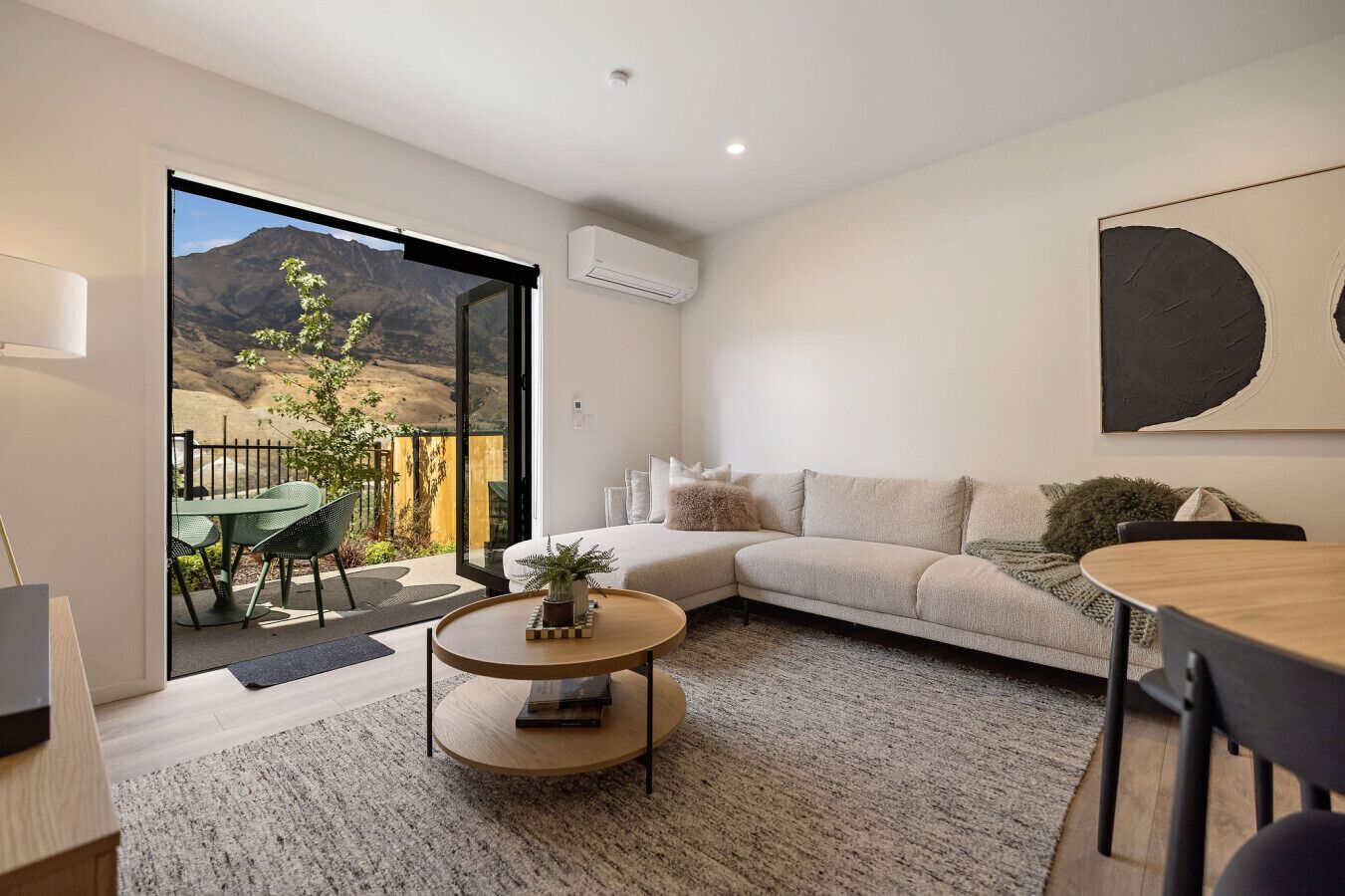 A modern living room with a sofa, coffee table, and a dining area.