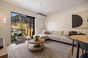 Ein modernes Wohnzimmer mit Sofa, Couchtisch und Essbereich.