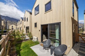 A modern wooden building with a patio area, outdoor seating, and a view of mountains. - Luxury Queenstown 2Bed Villa (Queenstown)