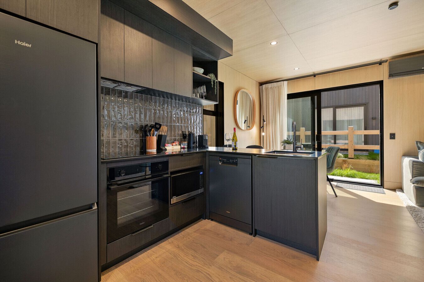 A modern kitchen with dark cabinetry, a built-in oven, and a dishwasher.