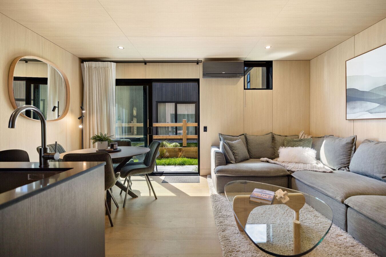 A modern living room with a sofa, a coffee table, and a dining area with a table and chairs.