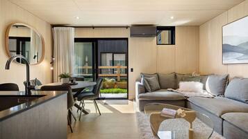 A modern living room with a sofa, a coffee table, and a dining area with a table and chairs.