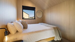 A bedroom with a bed, pillows, a bedside lamp, a window, and a circular mirror. - Luxury Queenstown 2Bed Villa (Queenstown)