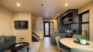 A modern living space with a sofa, coffee table, and a dining area with chairs. - Luxury Queenstown 2Bed Villa (Queenstown)