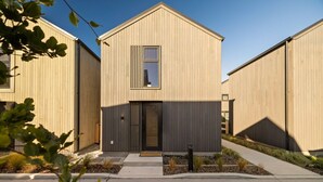A modern building with a symmetrical facade, a central entrance, and a small window above the door. - Luxury Queenstown 2Bed Villa (Queenstown)